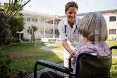 Doctor talking to senior woman sitting on wheelchair