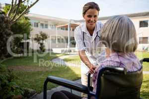 Doctor talking to senior woman sitting on wheelchair
