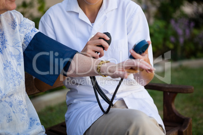 Female doctor examing senior woman in park