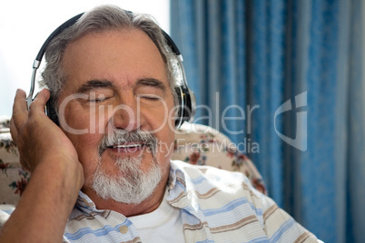 Senior man listening music through headphones in nursing home