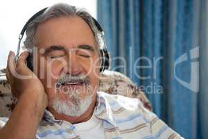 Senior man listening music through headphones in nursing home