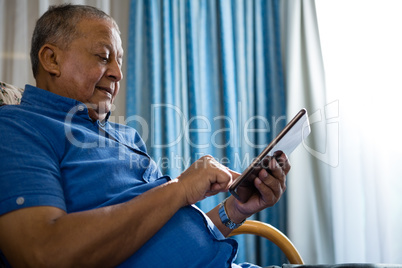 Low angle view of senior man using digital tablet in nursing home