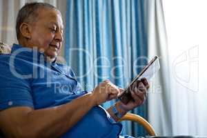 Low angle view of senior man using digital tablet in nursing home