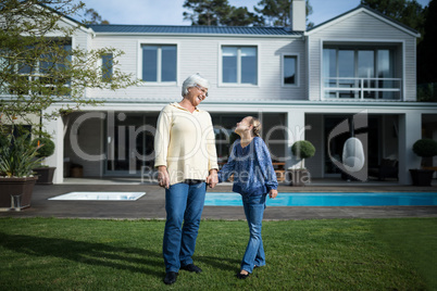 Smiling granddaughter and grandmother standing in garden