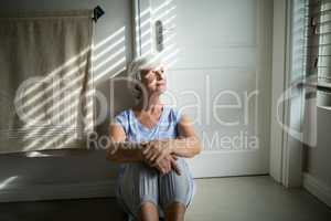 Tense senior woman looking through window in bedroom