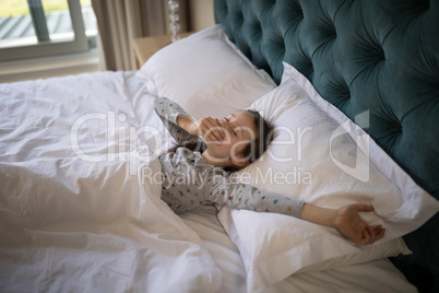 Girl yawning while stretching her arms in bed