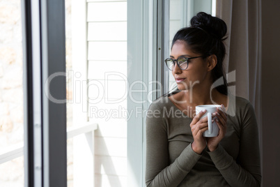 Woman with coffee cup by window