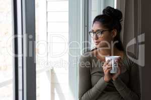 Woman with coffee cup by window