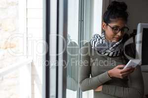 Young woman using phone by window