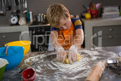 Boy kneading dough in kitchen