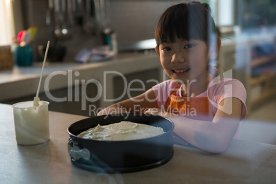 Portrait of girl with cake seen through glass in kitchen
