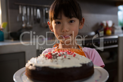 Portrait of girl with cake standing in kitchen