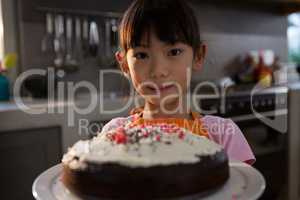 Portrait of girl with cake standing in kitchen