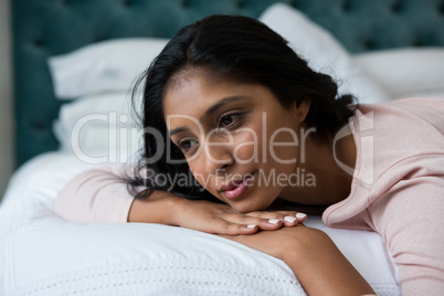 Thoughtful woman relaxing on bed