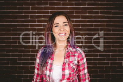 Woman smiling against brick wall