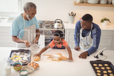 Boy preparing cookie dough with his father and grandfather in kitchen