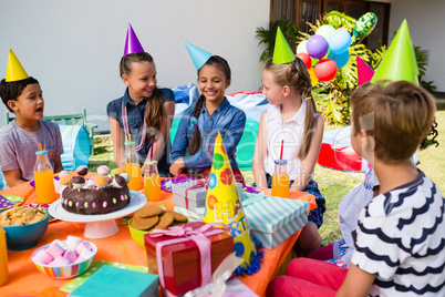 Happy children talking at table in yard