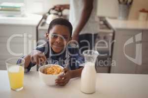 Smiling boy having breakfast cereals in kitchen