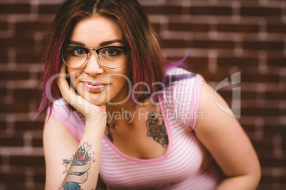 Smiling woman posing with hand on face against brick wall