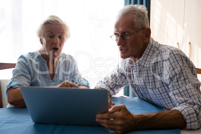 Senior man showing laptop to female friend in nursing home