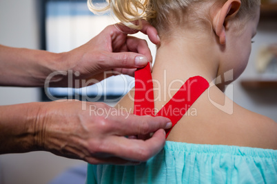 Physiotherapist sticking tape on girl patient