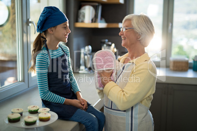Grandmother and granddaughter with oven gloves in the kitchen