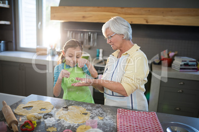 Grandmother showing a cut dough to her granddaughter