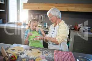 Grandmother showing a cut dough to her granddaughter