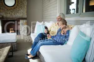 Smiling granddaughter and grandmother using digital tablet on sofa