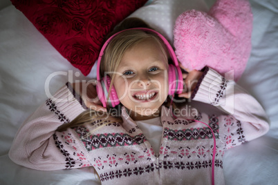 Girl listening to music on headphones while lying on bed