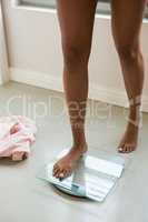 Low section of woman standing on weight scale