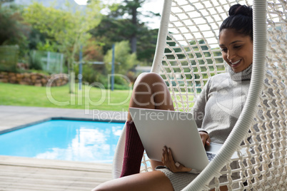 Smiling woman using laptop on swing