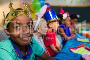 Portrait of smiling boy wearing crown with friends in background