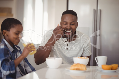 Father and son having breakfast in kitchen