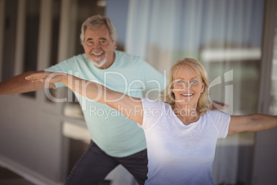 Smiling senior couple performing stretching exercise