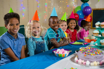 Portrait of smiling children sitting at table