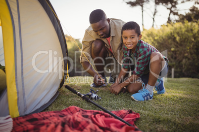 Father and son are setting up tent in park