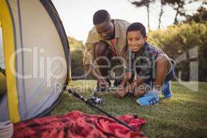 Father and son are setting up tent in park