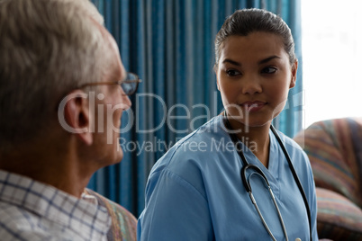 Doctor interacting with senior man while sitting in nursing home