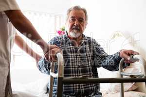 Female doctor standing by senior man holding walker in nursing home