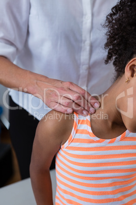 Physiotherapist giving neck massage to girl patient in clinic