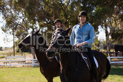 Two male friends riding horse in the ranch