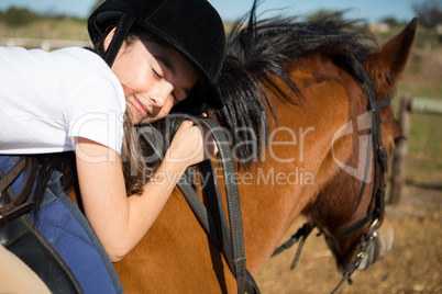 Cute girl embracing horse in the ranch