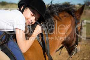 Cute girl embracing horse in the ranch