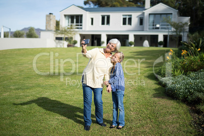 Grandmother and granddaughter taking selfie with mobile phone in garden