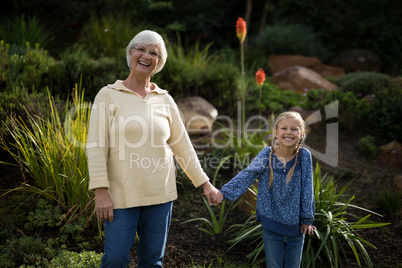 Smiling granddaughter and grandmother standing in garden