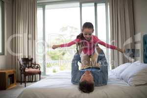 Playful father lifting her daughter on the bed