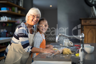 Grandmother and granddaughter posing while flattening dough