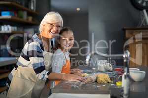 Grandmother and granddaughter posing while flattening dough