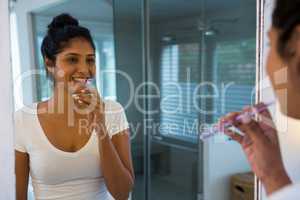 Woman brushing reflecting on mirror